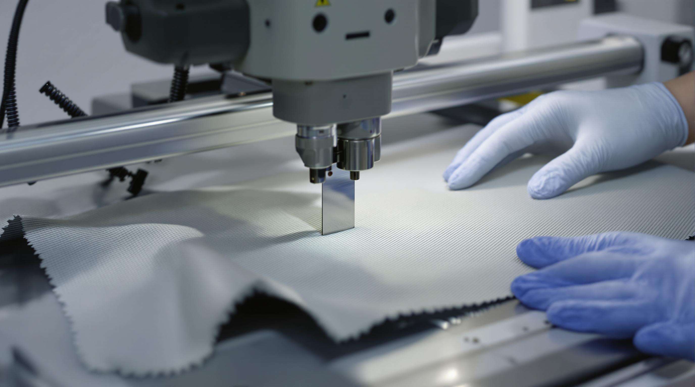 Laboratory test machines evaluating cut resistant fabric samples under a sharp blade