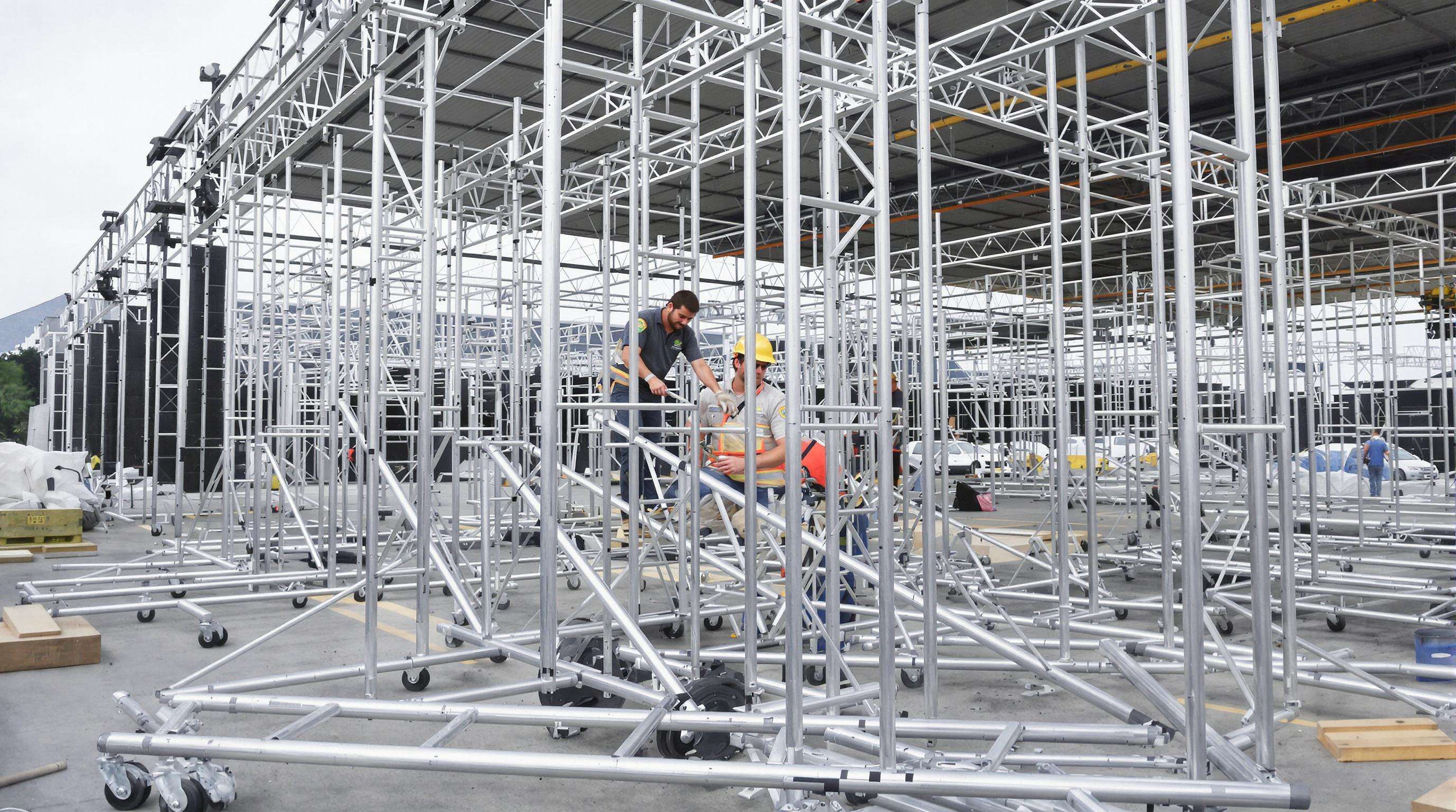 Event workers assembling a spigot truss system by hand at an outdoor venue