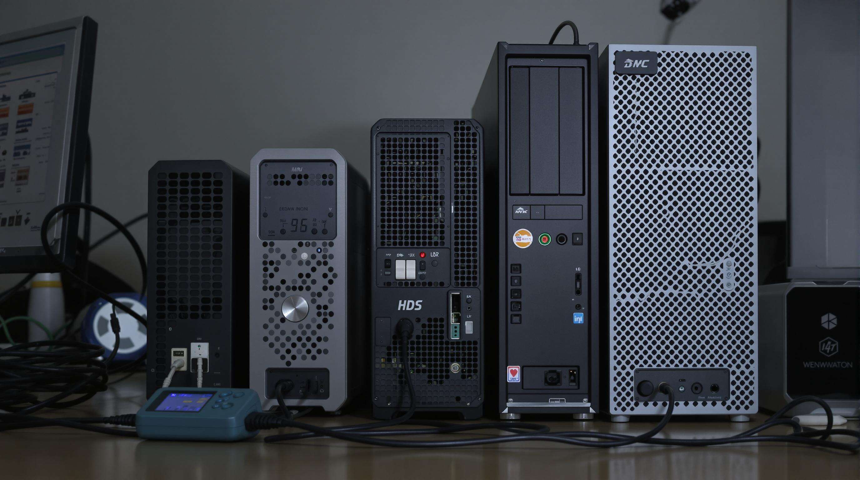 Photo showing mini PCs next to a traditional desktop computer on a desk, with energy meters and cables highlighting power use differences.