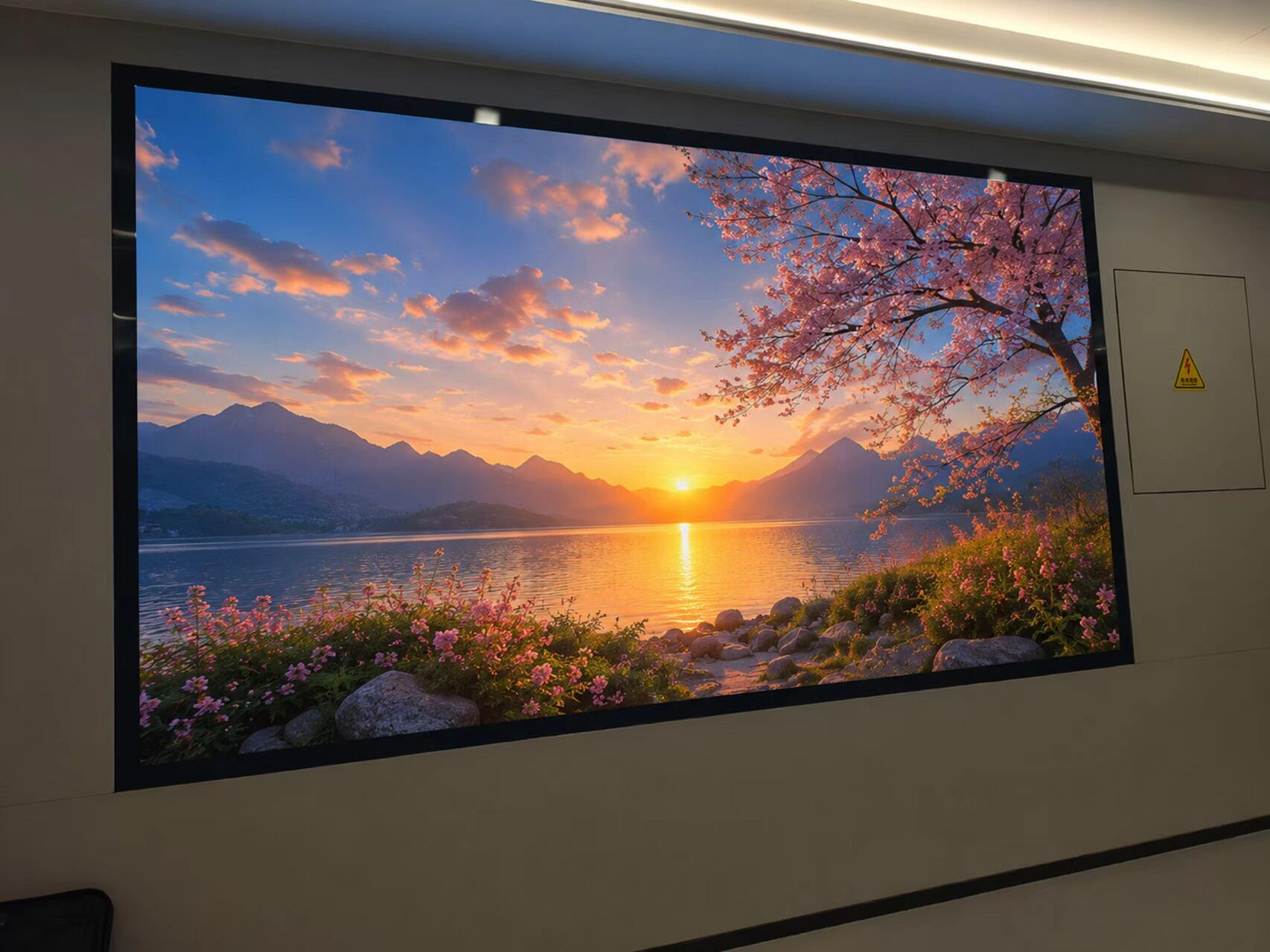 An ultrawide seamless LED display screen during installation in a corporate office, showing a bright green forest scene.