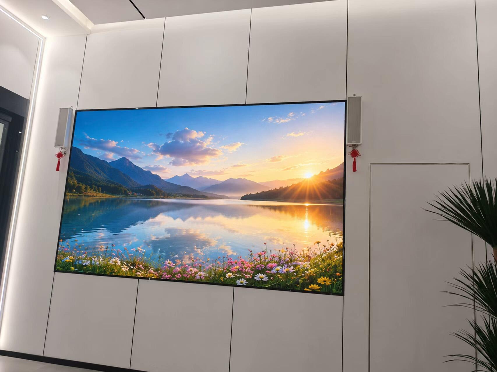 A large fine-pitch LED screen mounted on a modern paneled wall in a conference room, showing a crisp mountain and lake landscape.