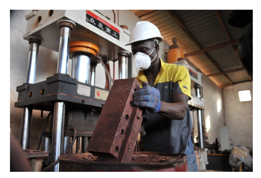 Plastic waste is pressed into blocks by a hydraulic press. Creativity from Ghanaian customers.