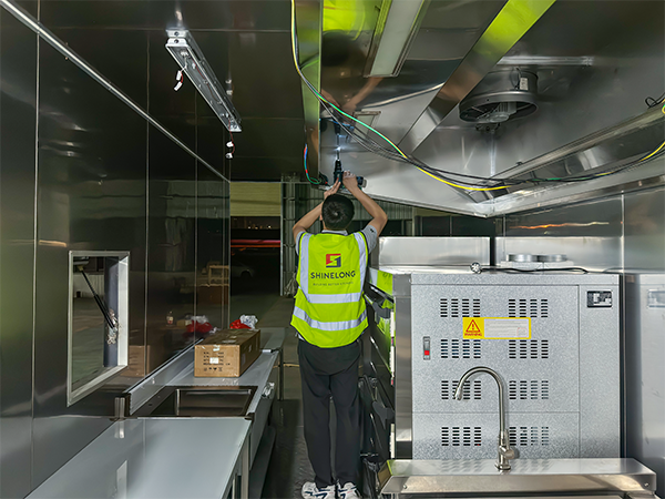SHINELONG technicians installing a ventilation hood inside a 40ft container kitchen..png
