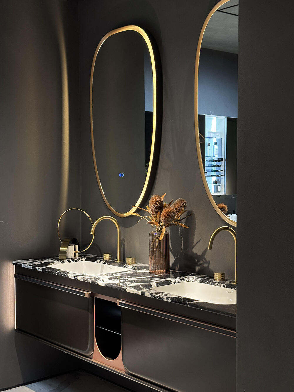Luxury Hotel Bathroom Vanity with Black Marble Countertop, Gold - Accented Oval Mirrors, and Modern Storage for a Sophisticated Bathroom Space
