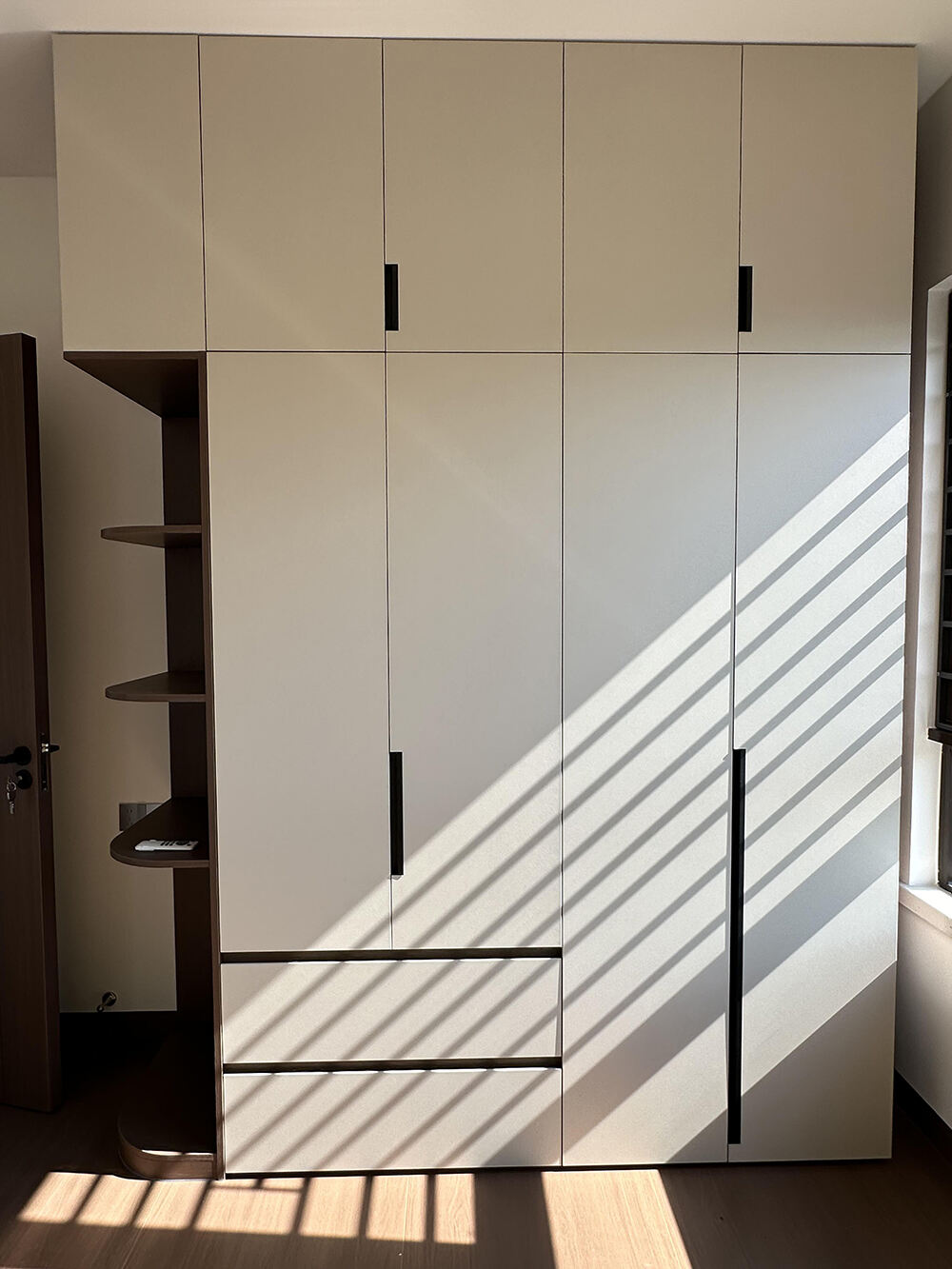 Custom - Made Light Beige Wardrobe with Dark Accents, Multi - Compartment Design, and Side Open Shelving for a Modern Bedroom Space