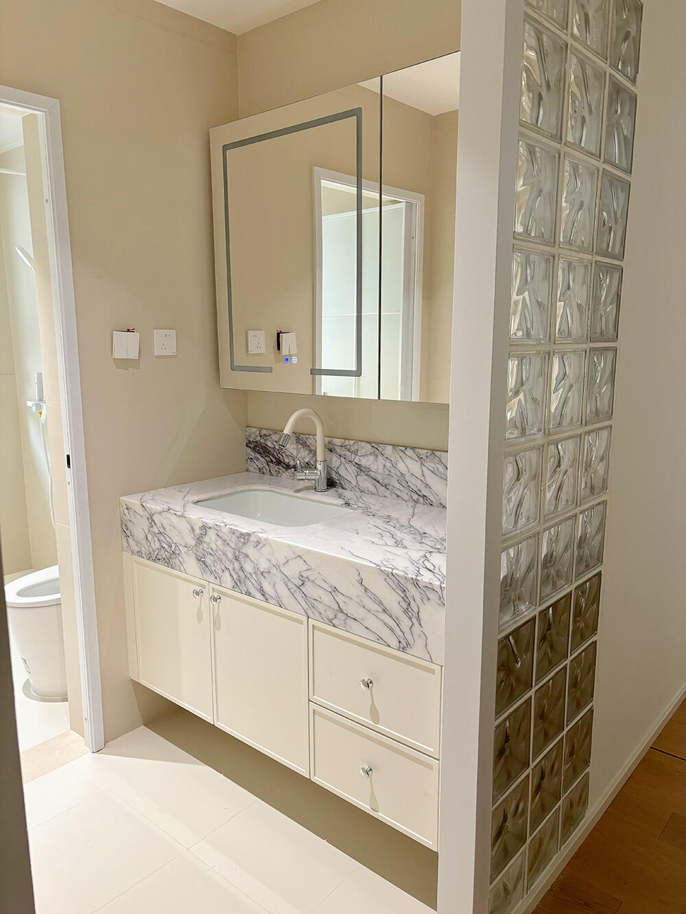 Elegant Beige Bathroom Vanity with Marble - Patterned Countertop, LED - Lit Mirror Cabinet, and Classic Design for a Luxurious Bathroom Space