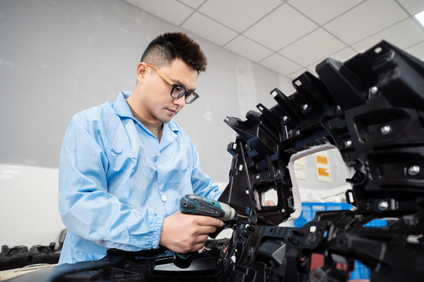 A technician is using a handheld device to inspect a car component.