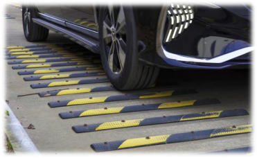 A black car is undergoing a test over a row of speed bumps.