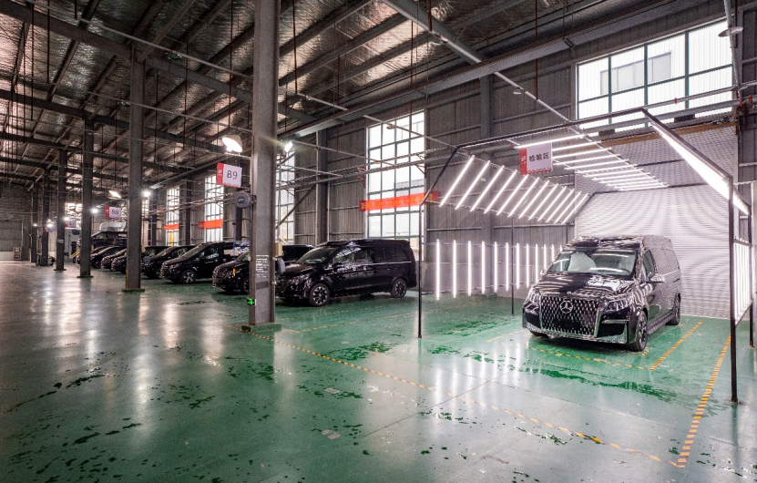 The interior of Shenzer Automotive's modification facility shows a series of vans undergoing customization.