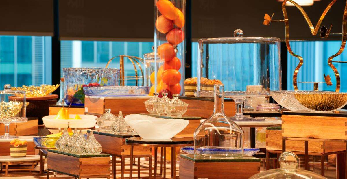 An elegant hotel buffet presentation display by Taitang, featuring luxury glassware, decorative glass cloches, and modern food risers that enhance the visual appeal of restaurant and banquet dining services.