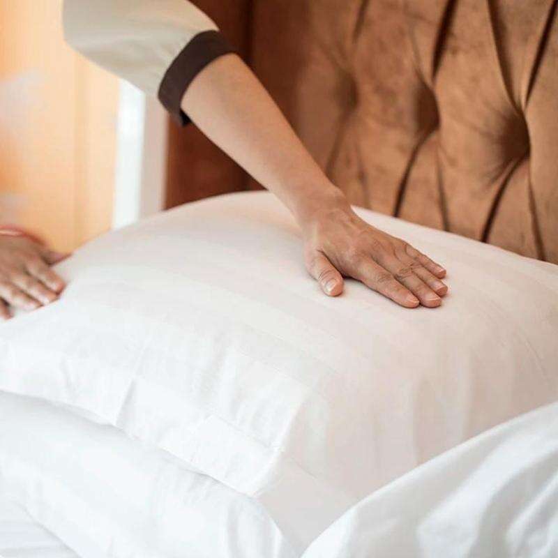 Hotel housekeeping professional arranging crisp white Taitang cotton sateen pillows on a luxury five-star hotel bed setup.jpg