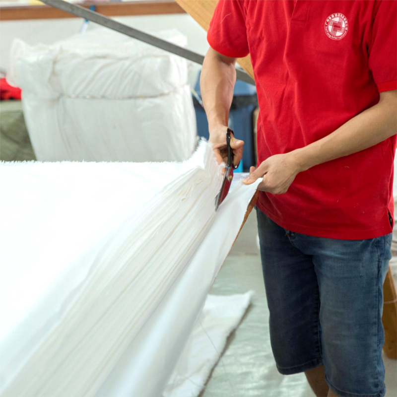 Skilled worker performing manual quality check and cutting on hotel linen fabric.jpg