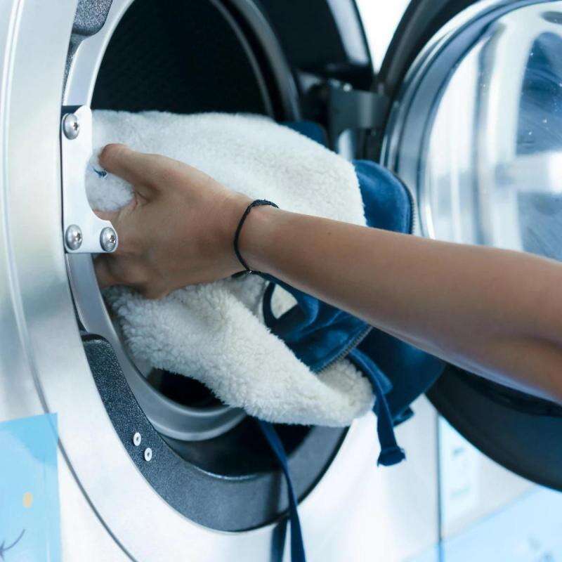 Laundry operator loading premium hospitality linens into a commercial stainless steel washing machine drum for industrial hotel bedding care.jpg