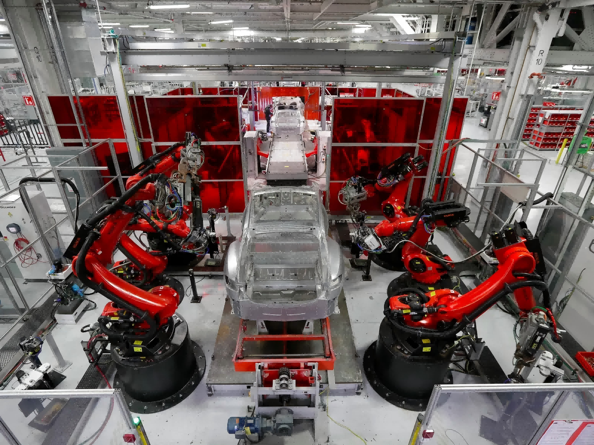 Gigafactory interior with automated robotic stations producing electric vehicles