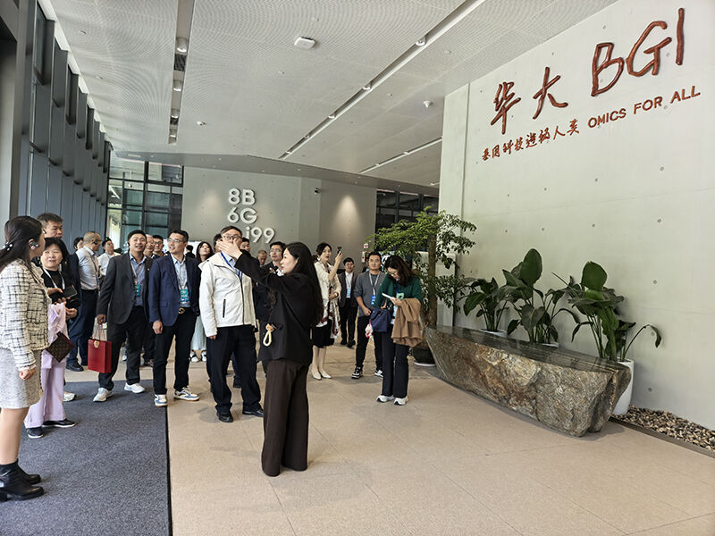 Xiamen University EMBA group receiving briefing at BGI Group reception hall, OMICS FOR ALL mission slogan on wall.jpg