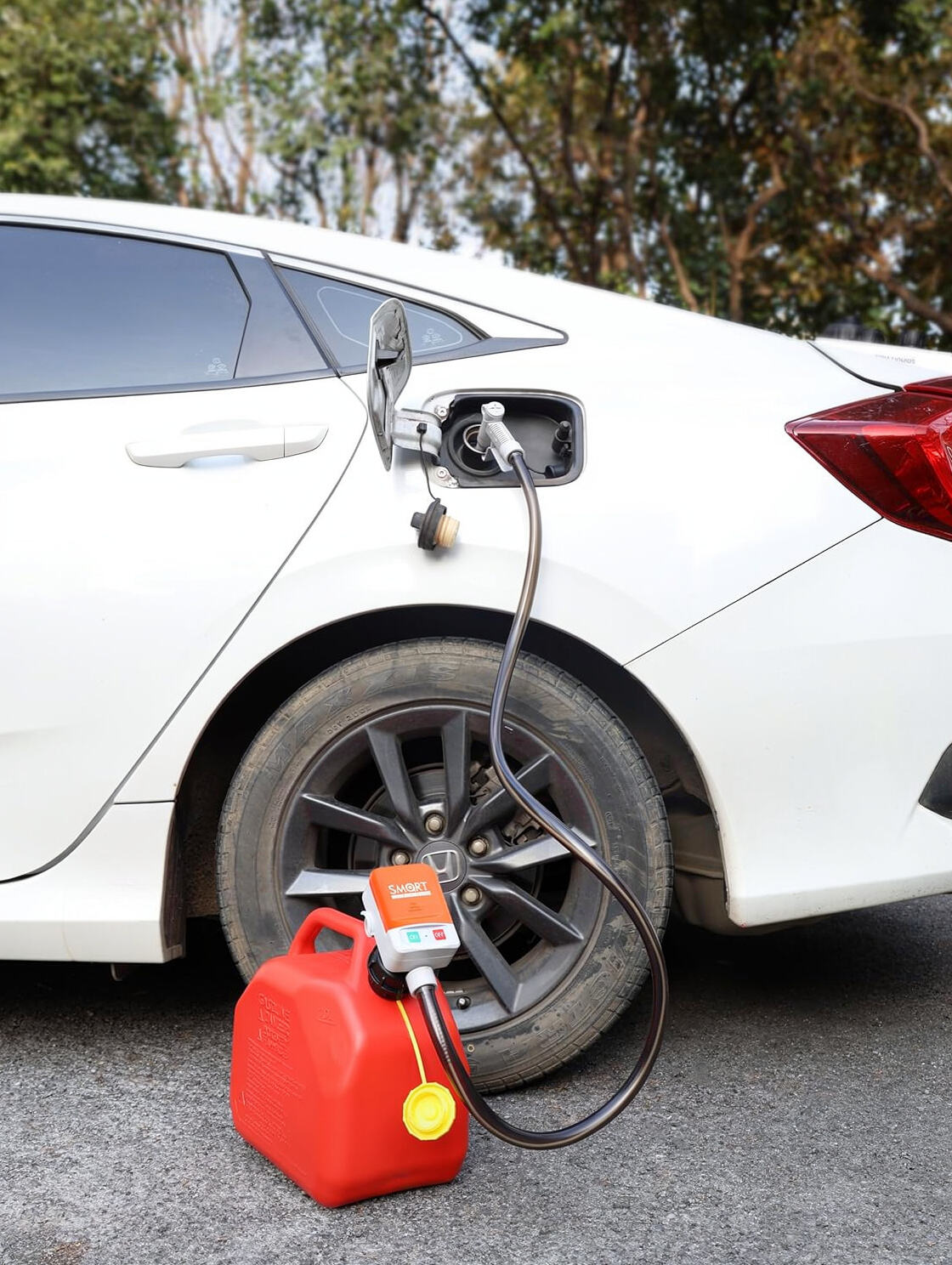 Portable electric fuel transfer pump transferring gasoline from red gas can to car fuel tank