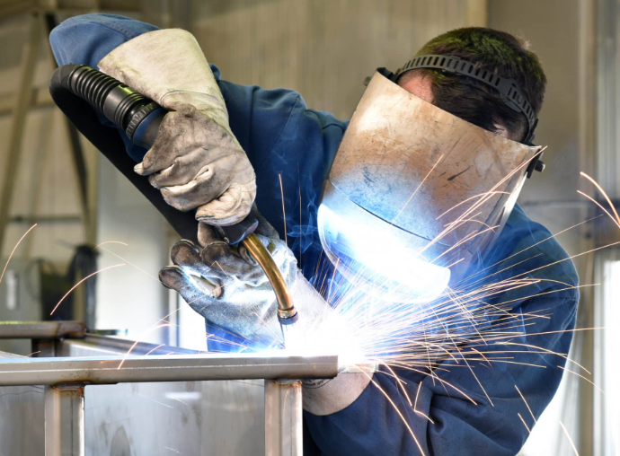 beginner practicing mig welding on clean flat steel in a safe workshop