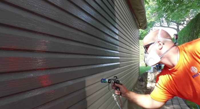 inspecting and repainting metal siding on a house exterior