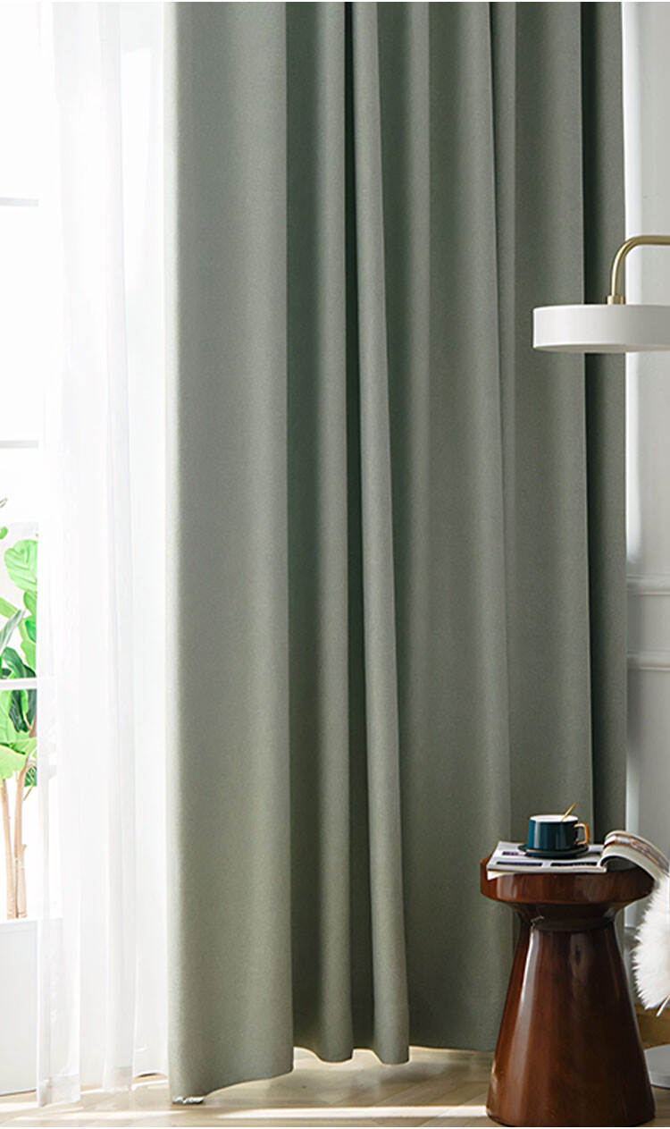 Interior scene with sage green curtains made from linen-look oxford fabric, styled with a side table and floor lamp.