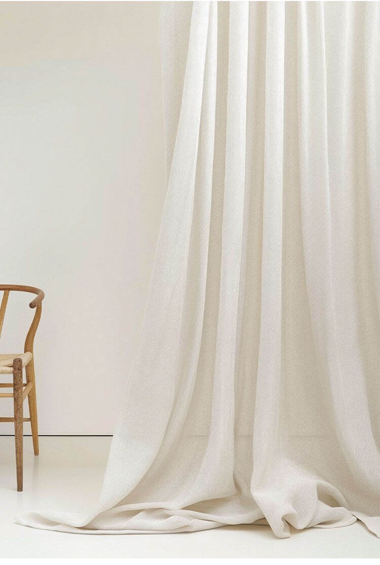 Minimal studio scene with heavy-denier slub sheer curtain fabric pooling on the floor, showing natural drape and textured surface.