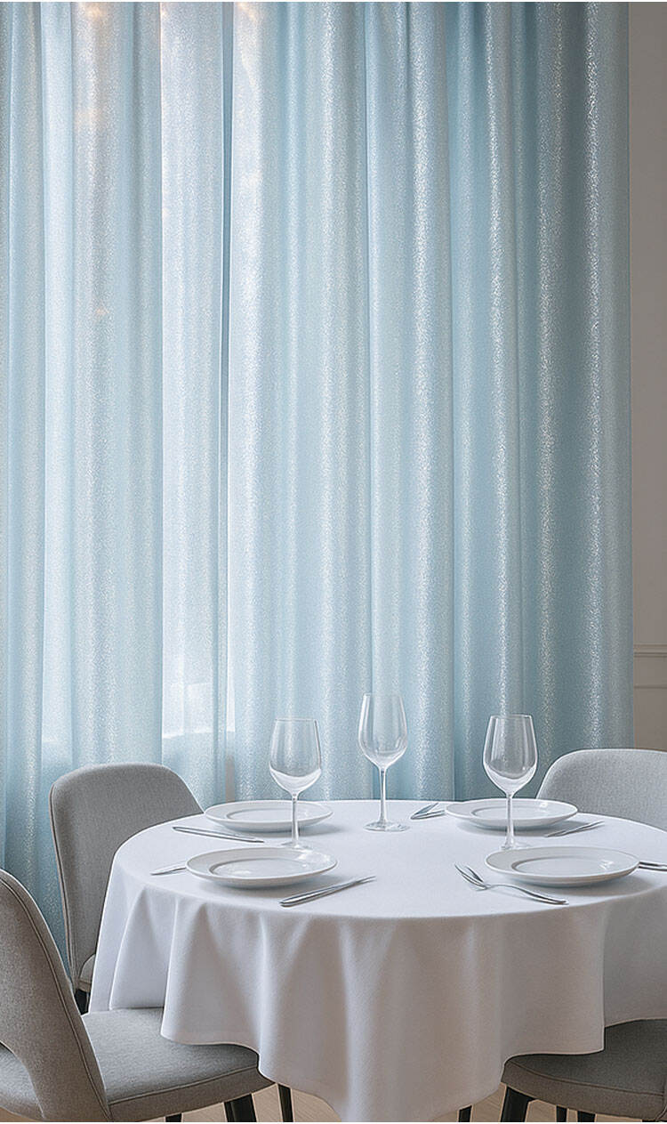Light blue shimmering curtains in a dining space, creating a refined, luminous atmosphere.