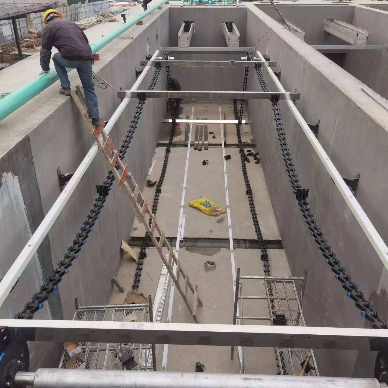 How do sludge scrapers help sewage treatment plants cut operating costs?